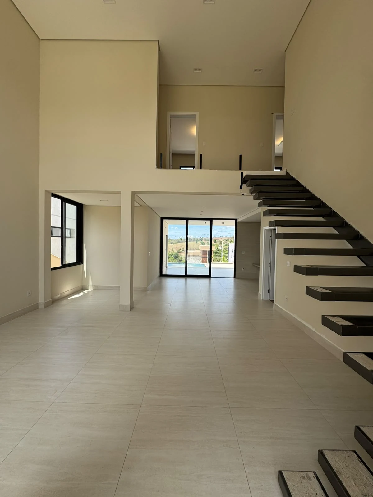 Casa Arezzo — Living com pé-direito duplo e escada em Gran Park Toscana · Vespasiano